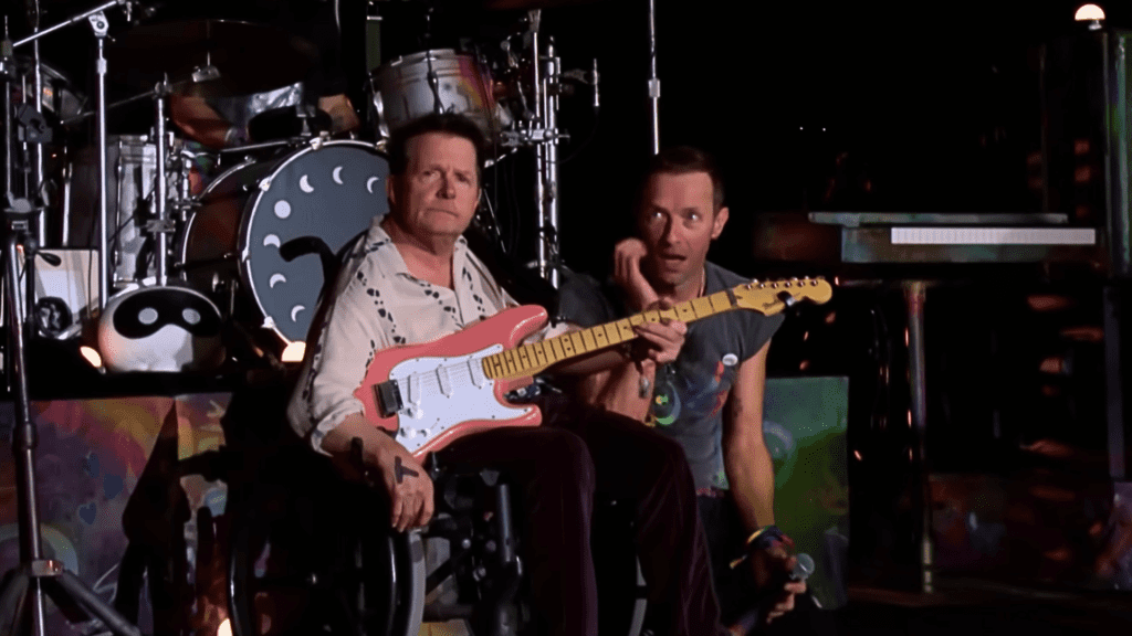 Ator Michael J. Fox (esq). e Chris Martin, vocalista do Coldplay, em show da banda no festival Glastonbury, no condado de Somerset, na Inglaterra | 29.jun.2024/Reprodução/BBC